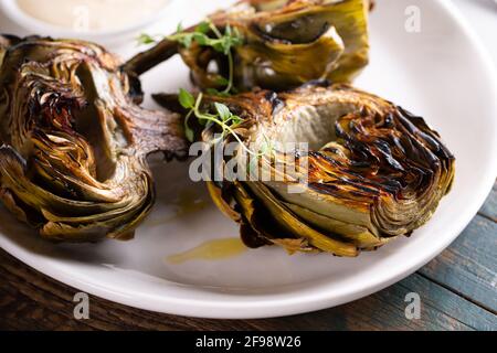 Grilled artichokes with a dipping sauce on a plate Stock Photo