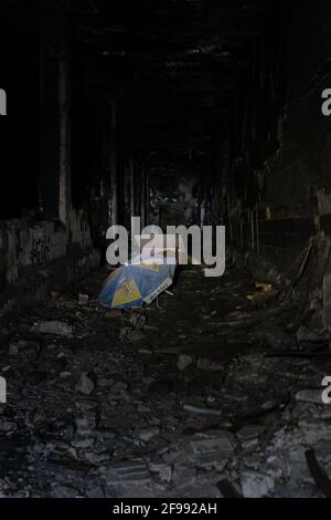 Vertical shot of a blue-yellow umbrella in the destroyed building Stock Photo