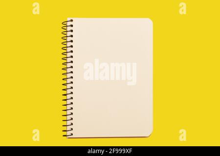 opened spiral notebook on a yellow surface Stock Photo