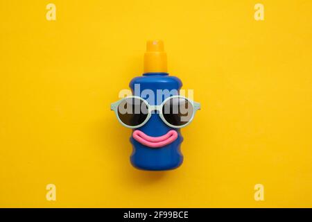 Happy sun block bottle wearing sunglasses and a smile on a yellow background Stock Photo