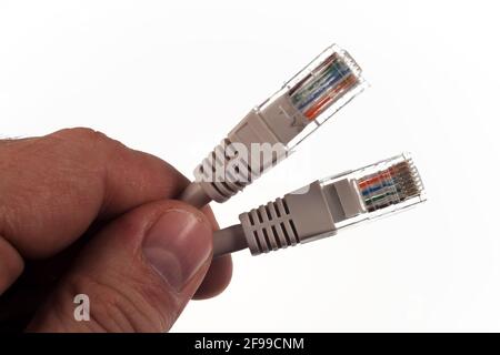 Pair of twisted Ethernet LAN network cables, in the hand of the master, Isolated on white background. Stock Photo