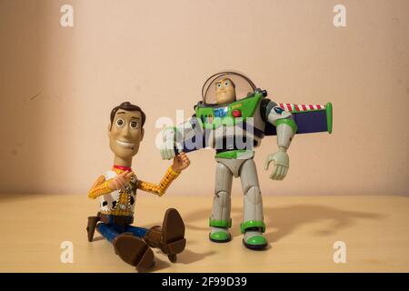 AVOLA, ITALY - Mar 21, 2021: Sheriff Woody and Buzz Lightyear toys, characters from Toy Story, laying close to each other holding their hands.