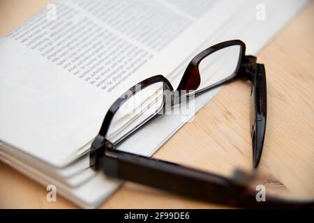 A closeup shot of a pair of reading glasses and a folded newspaper Stock Photo
