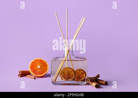 Reed diffuser with cinnamon and oranges on color background Stock Photo