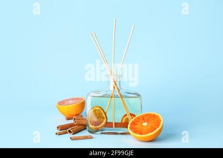 Reed diffuser with cinnamon and oranges on color background Stock Photo