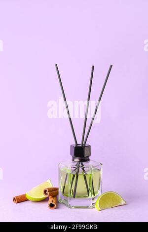 Reed diffuser with lime and cinnamon on color background Stock Photo