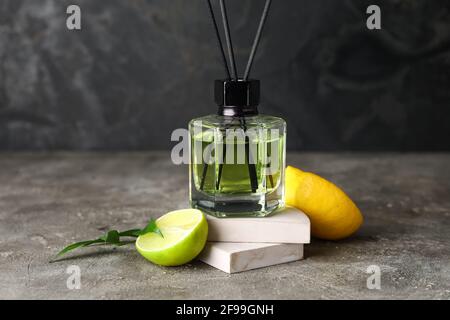 Reed diffuser with lemon and lime on grunge background Stock Photo