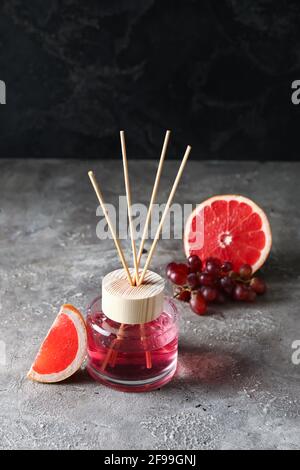 Reed diffuser with grapefruit and grapes on grunge background Stock Photo