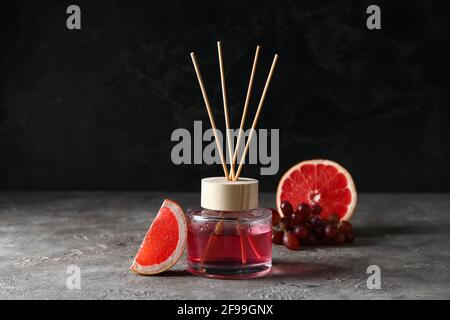Reed diffuser with grapefruit and grapes on grunge background Stock Photo