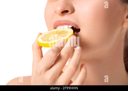 Beautiful young woman eating cut lemon on white background, closeup Stock Photo