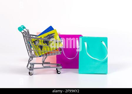 mini shopping cart with credit cards and colourful paper bags isolated on light background Stock Photo