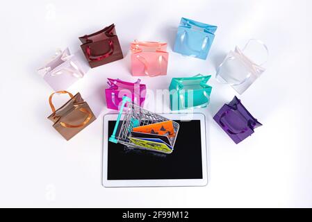 tablet, mini shopping cart with credit cards and colourful paper bags isolated on white Stock Photo