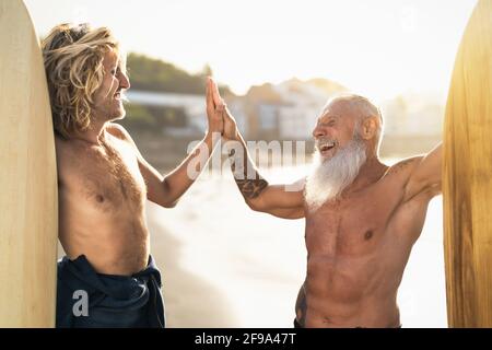Happy friends with different age surfing together - Sporty people having fun during vacation surf day - Extreme sport lifestyle concept Stock Photo