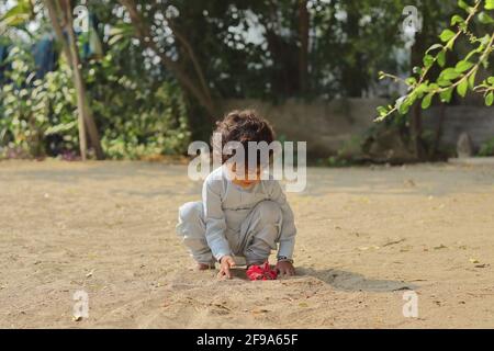 Close-up of An Indian child playing with a red hibiscus flower. Stock Photo