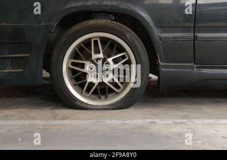 Closeup flat tire of abandoned car in parking lot Stock Photo