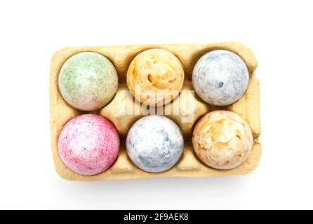 Brightly colored Easter eggs in an egg carton isolated on a white background