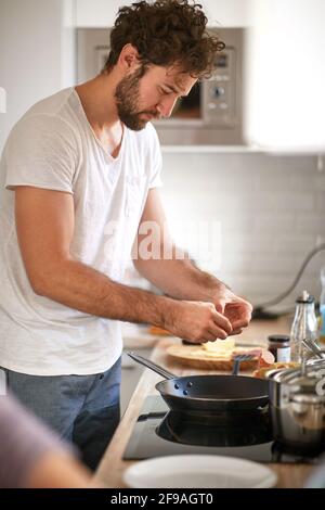 caucasian beardy guy with curly hair making breakfast. Stock Photo