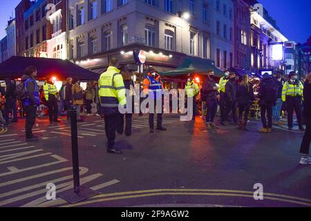 London, United Kingdom. 16th April 2021. Covid marshals and police on patrol in Old Compton Street, Soho. Crowds of people packed the bars and restaurants in Central London on the first Friday since lockdown rules were relaxed. Stock Photo