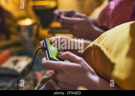 Close-up of young woman using joystick while playing video game with her friend at home Stock Photo