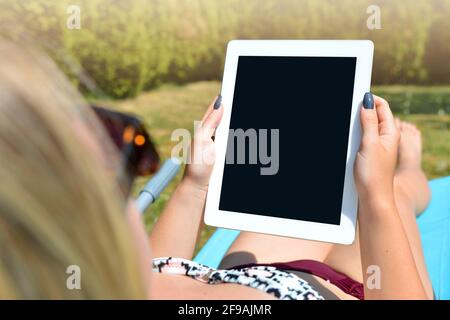 Woman lying on lounger in garden and using digital teblet. Stock Photo