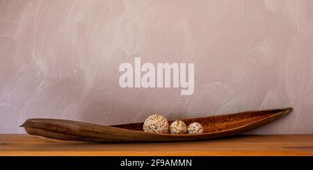Still Life: Palm leaf on wooden board against textured wall background Stock Photo