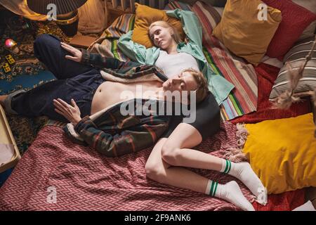 High angle view of young couple relaxing together on the bed among colored pillows at home Stock Photo