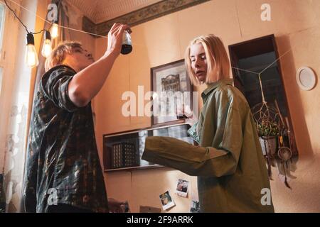 Young couple with alcohol drinks dancing together in the room during a party Stock Photo