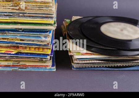 A collection of old comics, magazines, and vinyl records on a gray background. Lots of old shabby prints and music records from the last century. Coll Stock Photo