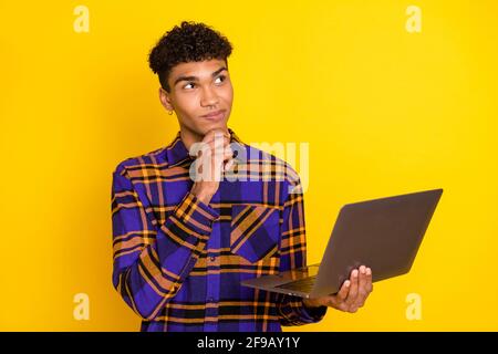 Photo portrait of young man working on computer thinking looking empty space isolated vibrant yellow color background Stock Photo