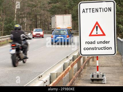 A sign beside road with traffic show warning message Road under construction. Stock Photo