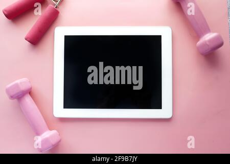  digital tablet with sports equipment on pink background 