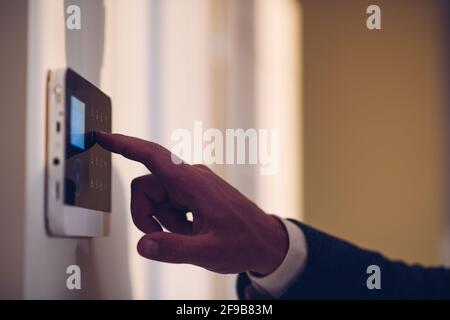 Hand and finger is pressing the alarm code on home alarm keypad. Stock Photo