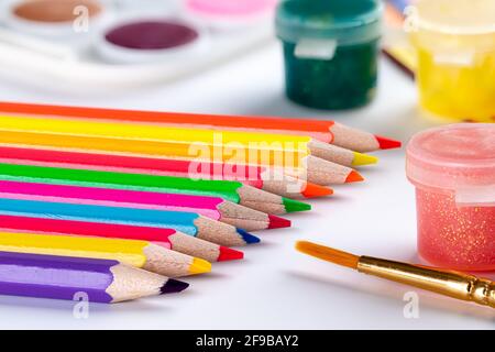 Closeup of school art supplies with colored pencils and paint on a white table Stock Photo