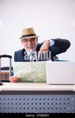 Aged male employee preparing for travel in the office Stock Photo
