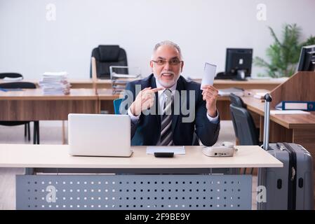 Aged male employee preparing for travel in the office Stock Photo