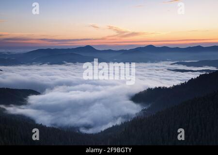 Sunrise. Amazing landscape with high mountains, fog and sky. The early morning mist. Majestic spring day. Dense fog with beautiful light. Free space f Stock Photo