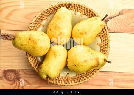 Five tasty natural pears, in a ceramic plate, on a wooden table. Stock Photo