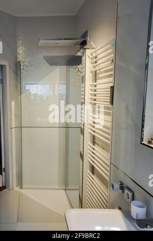 Floor-level shower with an exceptionally large overhead shower in a modern look. In the foreground a stylish towel radiator Stock Photo