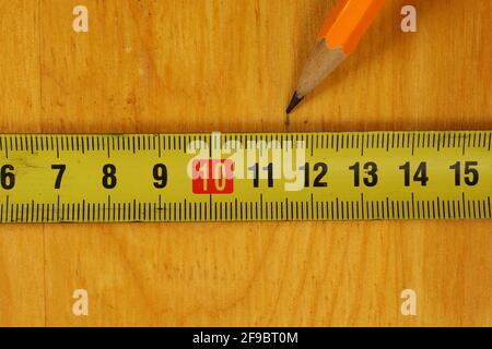 Carpentry. Pencil marking of a wooden cutting board with a metal measuring tape. Stock Photo