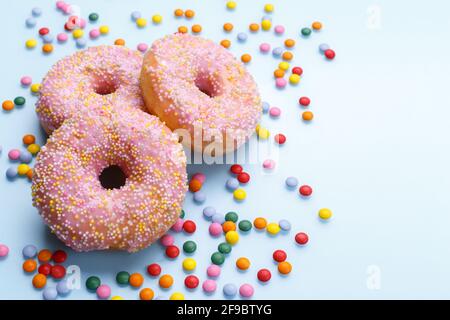 Pink doughnuts and candies on blue background, copy space flat lay Stock Photo
