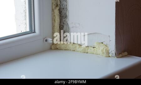 Installation of windows. Polyurethane foam on the slope of the window. Sealing window slopes. Stock Photo