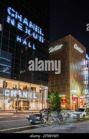 Facades of the Cartier and Chanel stores lit at night, Ginza, Tokyo, Japan Stock Photo