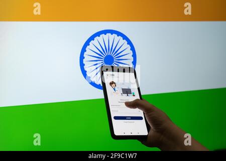 Man woman holding the Co-WIN covid19 coronavirus vaccination tracking app against a flag of India as the innoculation is being done to ensure immunity Stock Photo