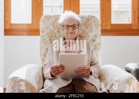 smiling elderly woman using a tablet on the sofa Stock Photo
