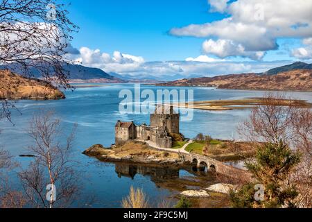 EILEAN DONAN CASTLE LOCH DUICH HIGHLANDS SCOTLAND BLUE SKY AND A BLUE LOCH IN SPRING SNOW CAPPED MOUNTAINS IN THE DISTANCE Stock Photo