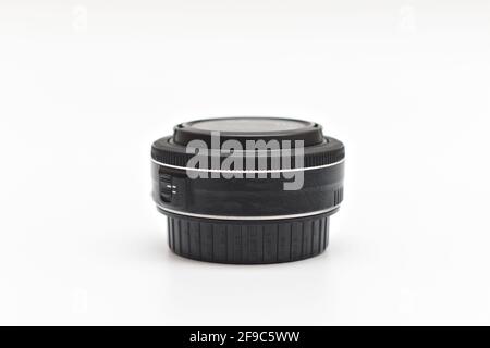 Small thin black pancake lens for DSLR camera with caps on on white surface Stock Photo