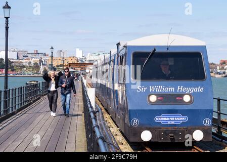 Southend on Sea, Essex, UK. 17th April, 2021. The day has been bright and sunny in the seaside town, but with a chill wind. Many people have visited to enjoy the seafront and its famous pier. Young adults, people walking on the walkway as the pier train passes Stock Photo