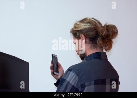 Young Hispanic man shooting his laptop screen on the phone isolated on a white background Stock Photo