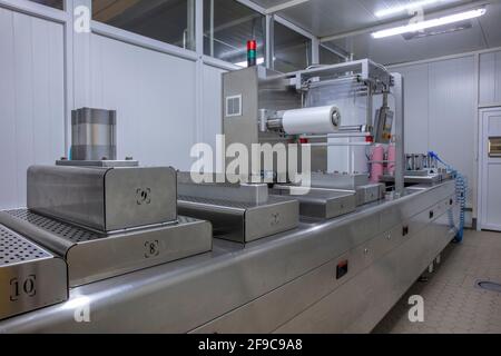 Processing of Packaging of butter and Cheese on food vacuum packaging sealing machine in food industrial factory. Packing food butter and Cheese in pr Stock Photo