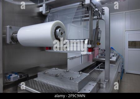 Processing of Packaging of butter and Cheese on food vacuum packaging sealing machine in food industrial factory. Packing food butter and Cheese in pr Stock Photo